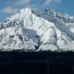 Alaska megatsunami climate risk, showing a fjord with melting glaciers and a large wave